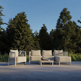 Kirra Lounge Chair i sandfarget olefin-tekstilstoff med aluminiumsramme, utendørs miljø.