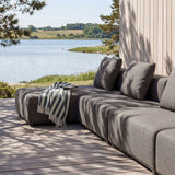 Mørk grå modulsofa med sjeselong fra sackit Norway på treterrasse ved vannet med puter og stripete pledd i nordisk utemiljø