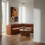 Brun Fjord hjørnesofa fra sackit i en lys nordisk stue med kunst på veggen rundt sofabord og grønne grener