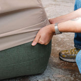 Hånd som justerer et vannavstøtende og vindtett trekk på en grønn Soft Sofa Outdoor pouf fra sackit for beskyttelse mot vær og vind