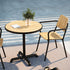 Rundt utendørs Kirra Café Table i pulverlakkert aluminium med teakbordplate på en terrasse.
