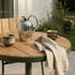Kirra Café Table utendørs bord i pulverlakkert aluminium og ubehandlet teak, rund form, naturfarger.