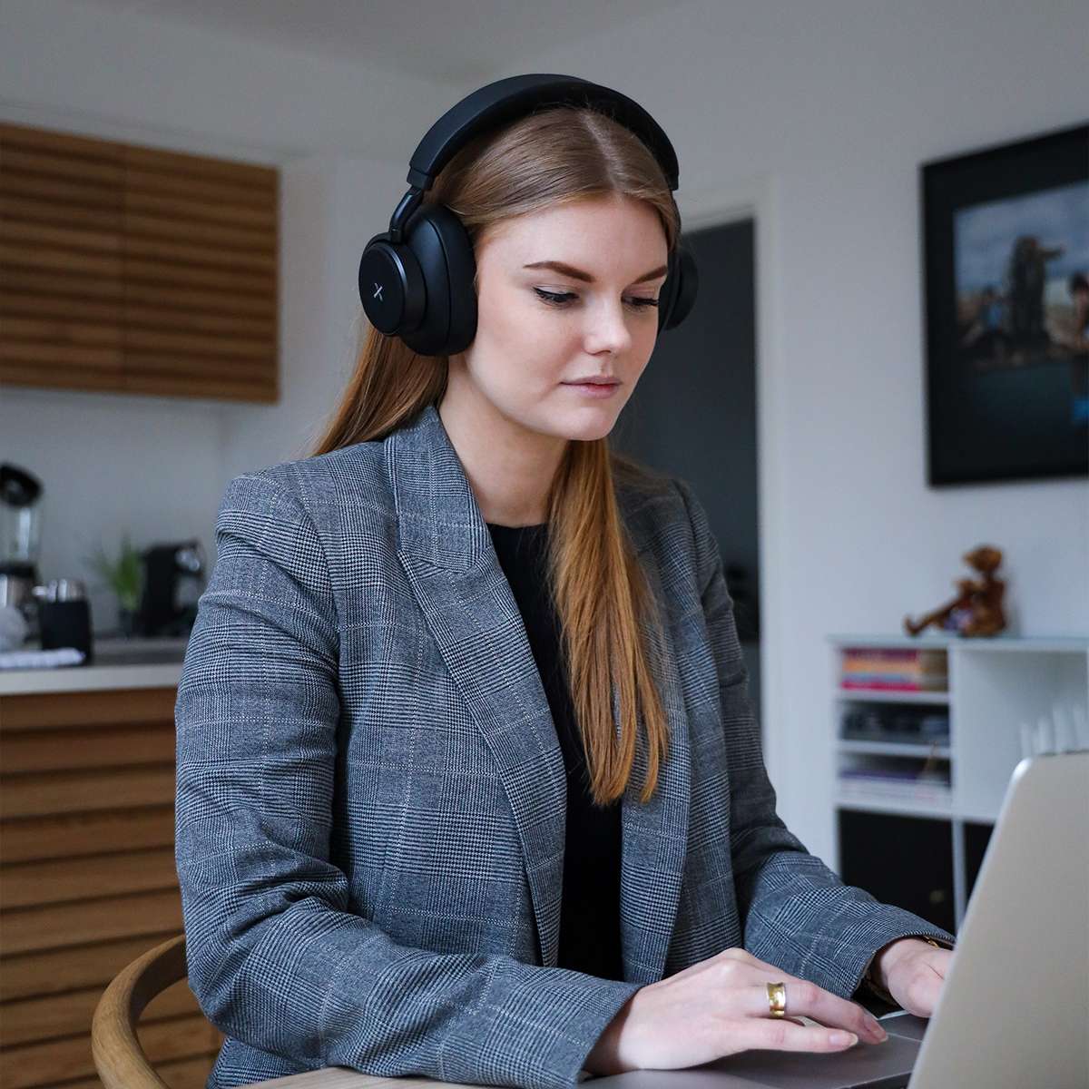 Kvinne med trådløse sackit Touch 410 hodetelefoner med støydemping som arbeider på laptop hjemme