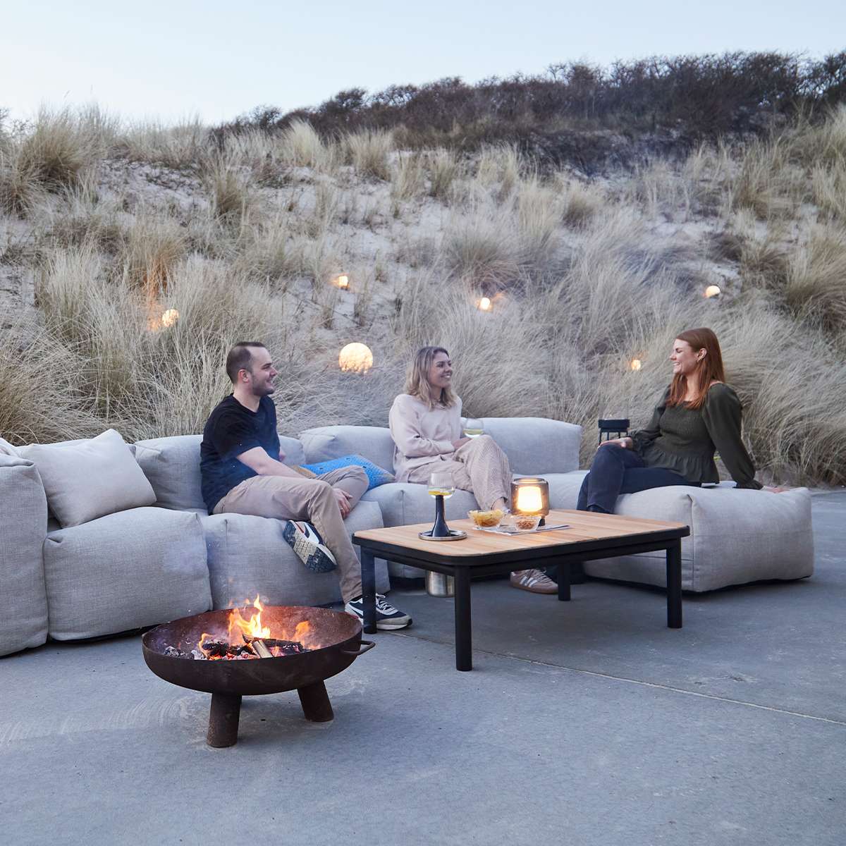 Soft Sofa Outdoor Lounger i Kirra Sand med myke puter og lavt sete, plassert utendørs.