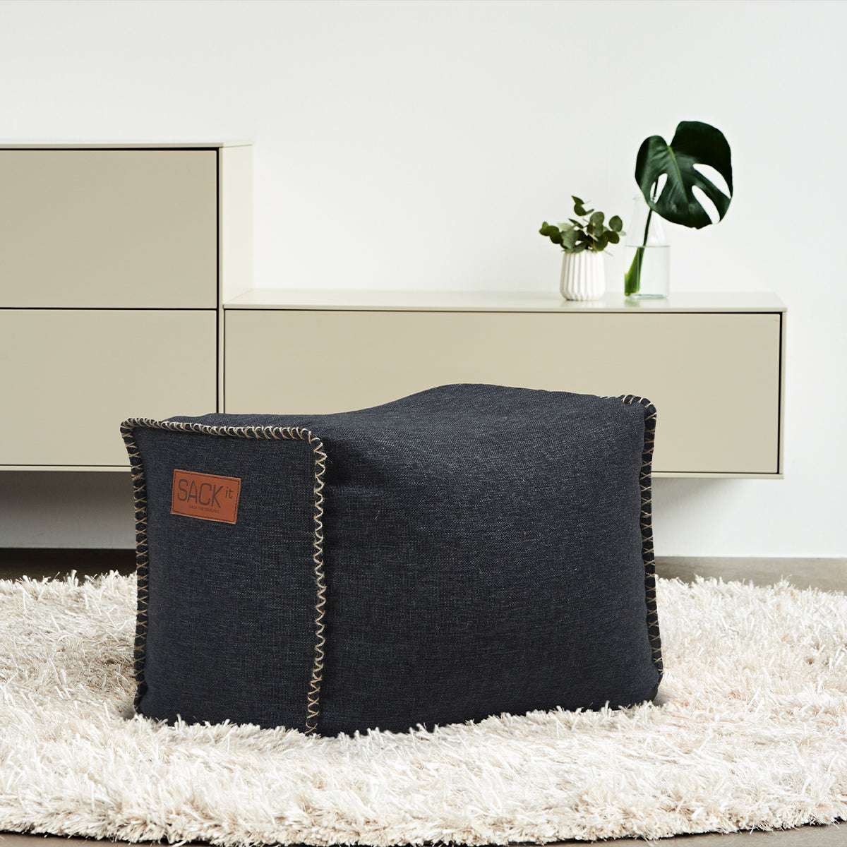 Cobana Square Pouf i svart olefinfiber med firkantet form og håndsydde sømmer.