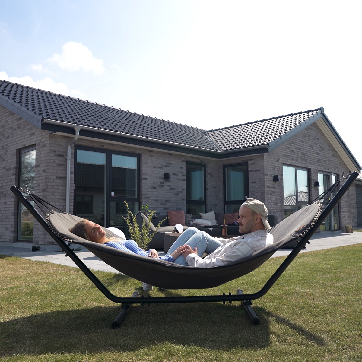 Cobana Hammock hengekøye i grå olefin med svart pulverlakkert aluminiumstativ utendørs.