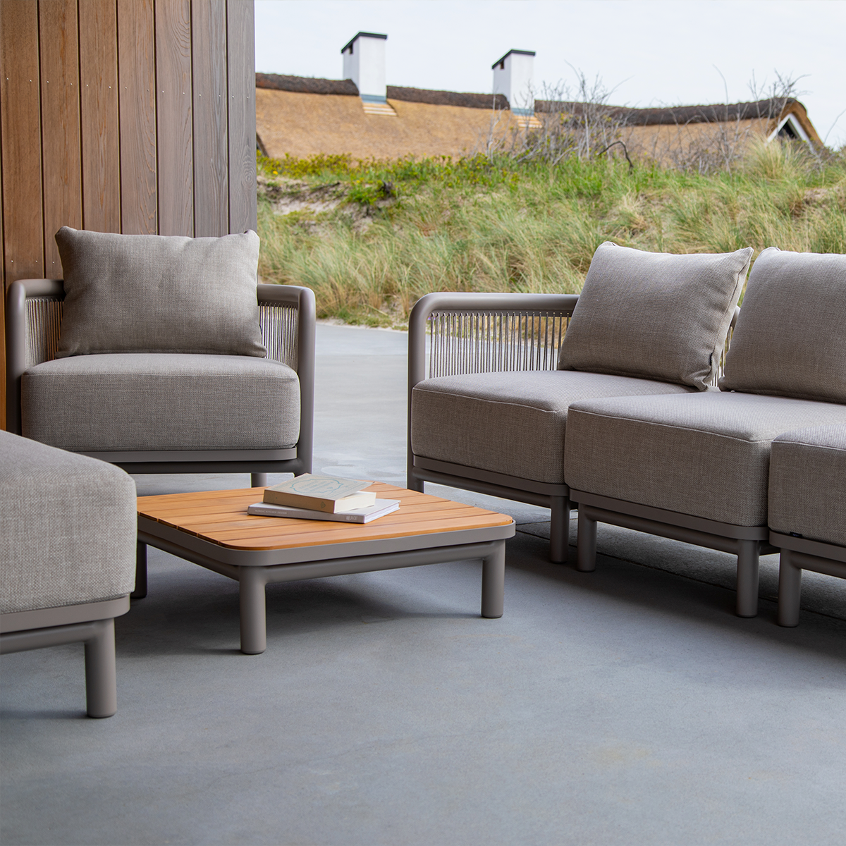 Kirra Lounge Sofa modul i sandfarget olefin med pulverlakkert aluminiumsramme, sett fra siden.
