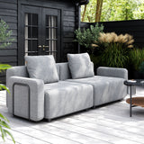 Grå modulbasert Cobana loungesofa med armlener på en lys terrasse i en frodig nordisk hage fra sackit