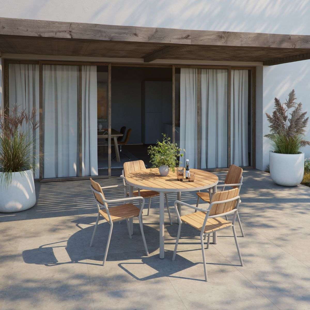 sackit Kirra spisegruppe med rundt spisebord og fire stoler på solrik terrasse med moderne hus og grønne planter