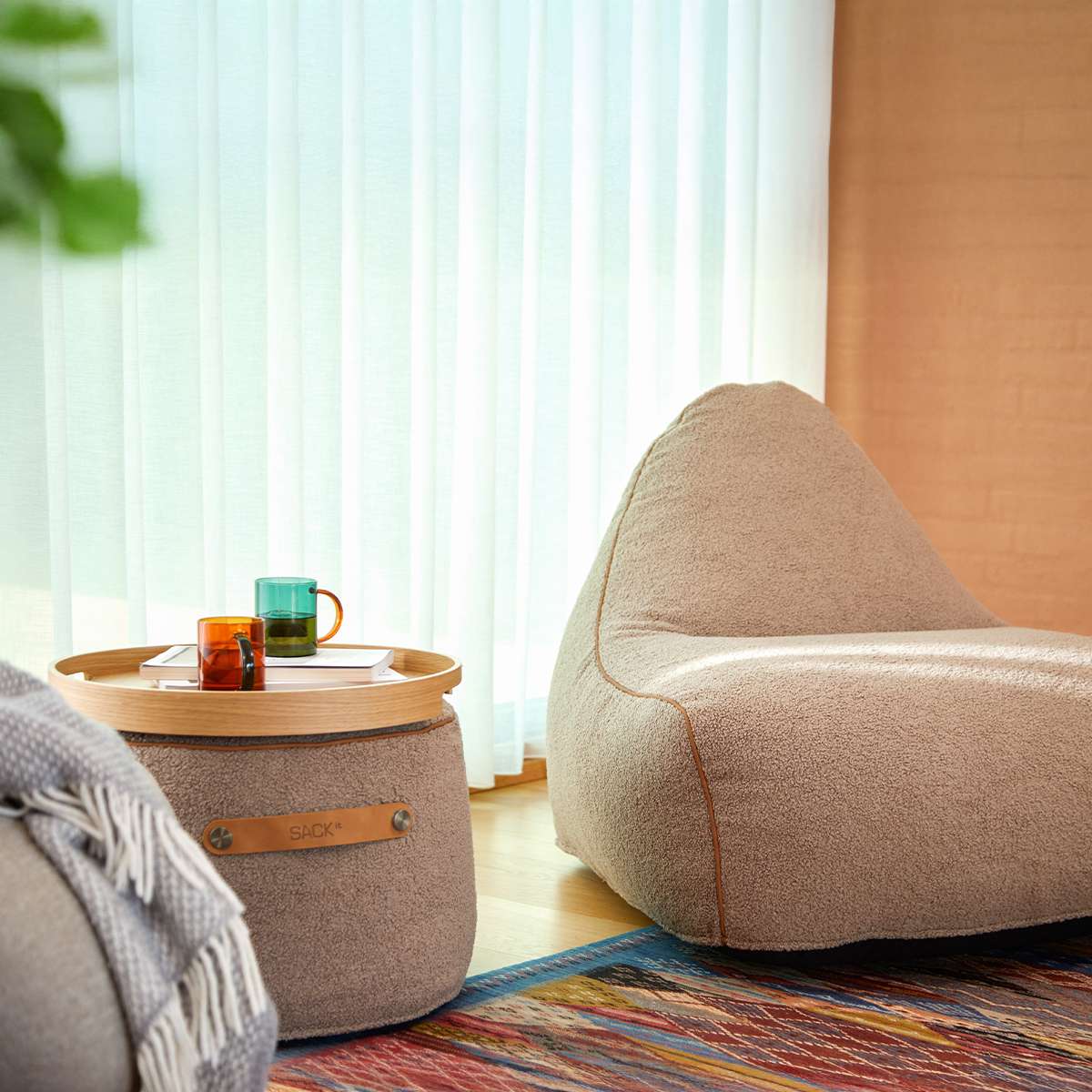 Rund SACKit Pouf Indoor i Teddy Brown tekstil med sklisikre punkter og stropp på siden.