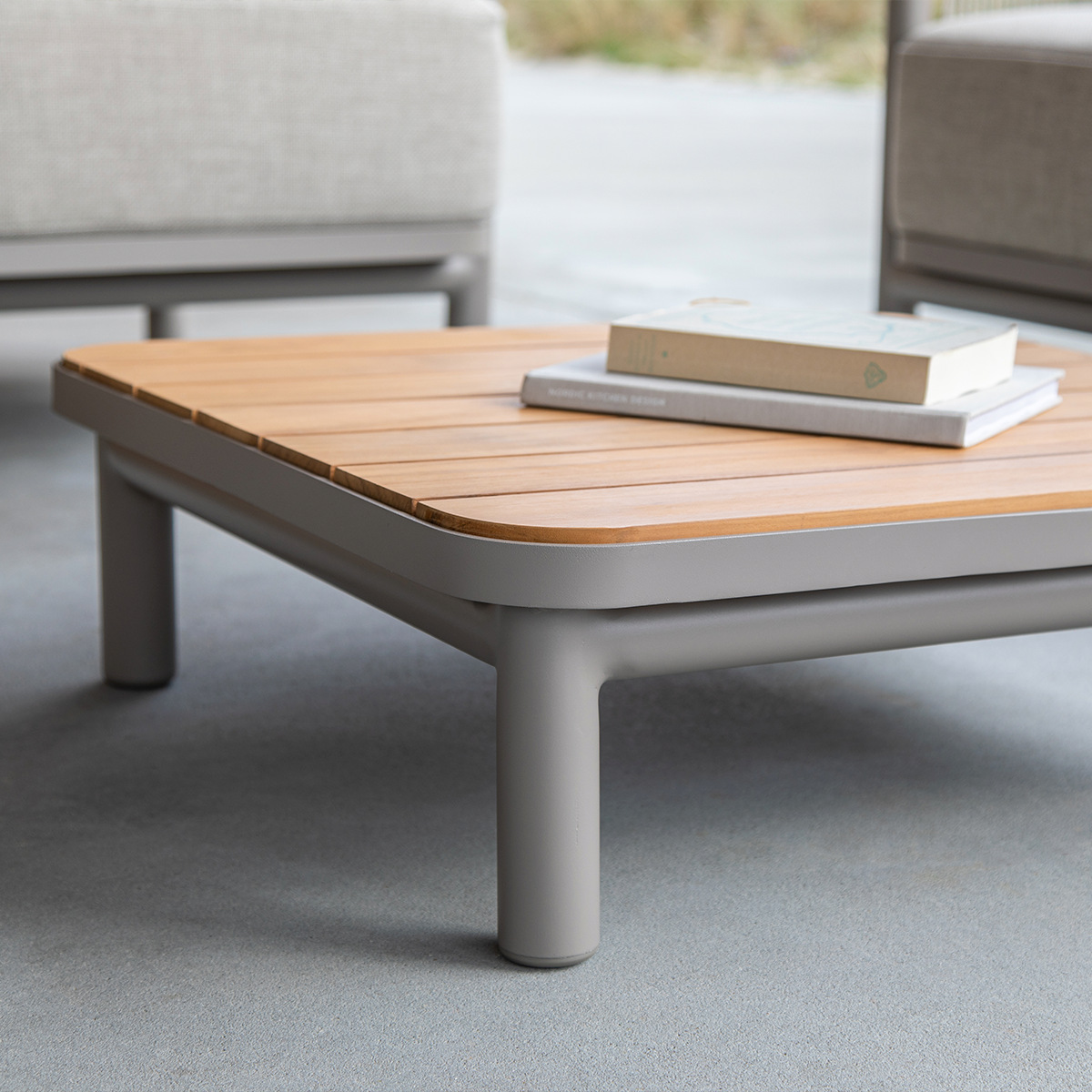 Kirra Lounge Sofa i sandfarge med to seter og Kirra bord i aluminium og teak i uterom.