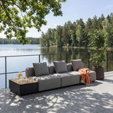Modulbasert grå utesofa med puter og oransje pledd på terrasse ved innsjøen designet i Danmark av sackit Norway for nordisk vær