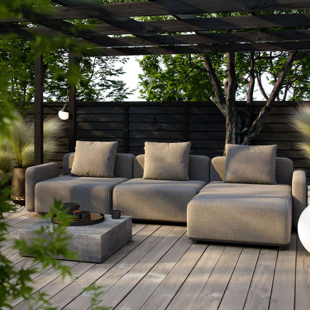 Modulær lounge sofa med pouf og beige puter på en treterrasse under pergola i en frodig hage fra sackitarsuaq