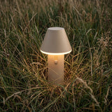sackit Cone trådløs bordlampe med varm belysning plassert i høyt gress og designet for både innendørs og utendørs bruk