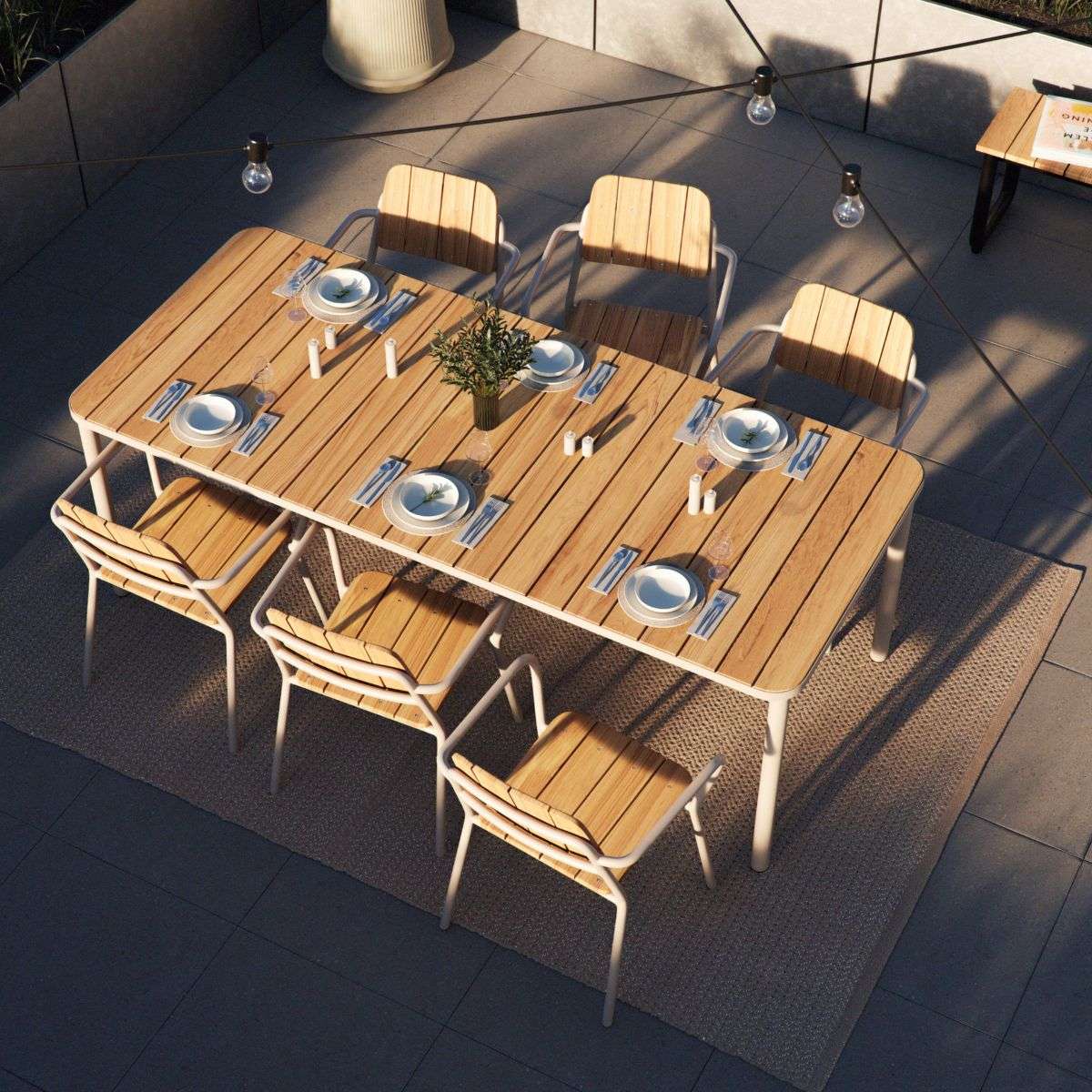 Utendørs spisegruppe med rektangulært spisebord i tre og seks stoler med armlener dekket til middag på en moderne terrasse fra sackit