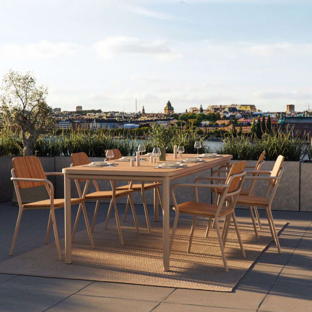 Utendørs spisegruppe med Kirra spisebord og seks stoler fra sackit i en solrik takterrasse med utsikt over byen