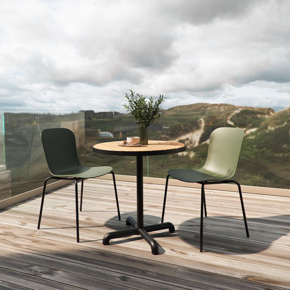 sackit Kirra kafésett med rundt svart utebord og to grønne stoler på en treterrasse med glassrekkverk og utsikt over kystlandskapet