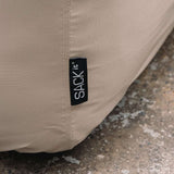 Detalj av beige trekk til Soft Sofa pouf med synlig søm og sackit merke, designet for å beskytte utemøbelet mot vær og vind
