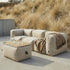 Beige utendørs pouf fra sackit som fotskammel og ekstra sitteplass foran en myk lounge sofa på en solrik terrasse ved sanddyner