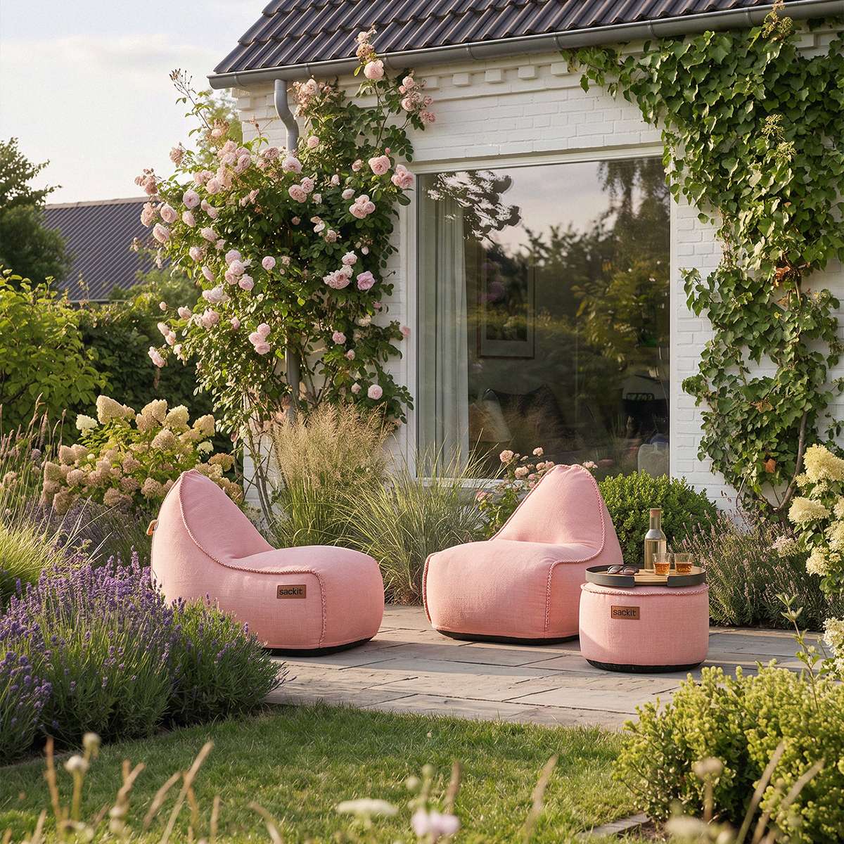 To rosa Cobana loungestoler og en matchende puff fra sackit på en frodig terrasse omgitt av blomster og grønne planter