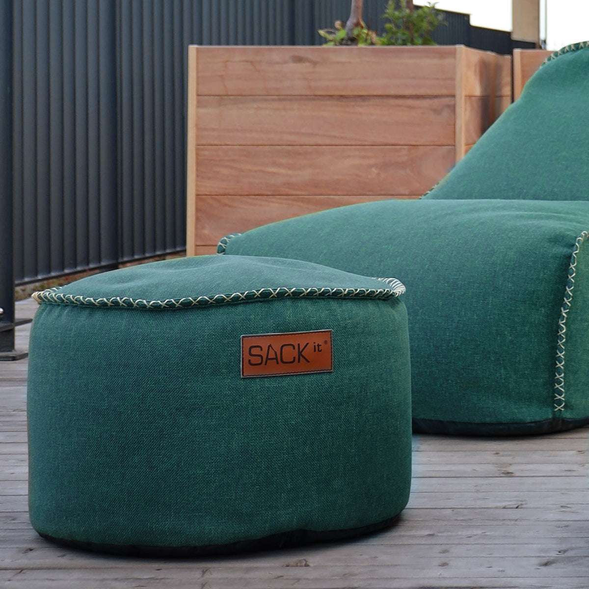 Rund Cobana Pouf i grått stoff med håndsydde sømmer, brukt som puff eller ekstra sitteplass.