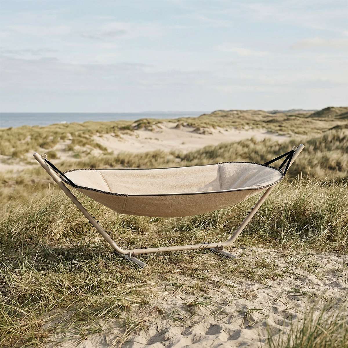 Cobana hengekøye fra sackit i beige tekstil på pulverlakkert stativ ved stranden omgitt av sanddyner og gress for avslapning utendørs