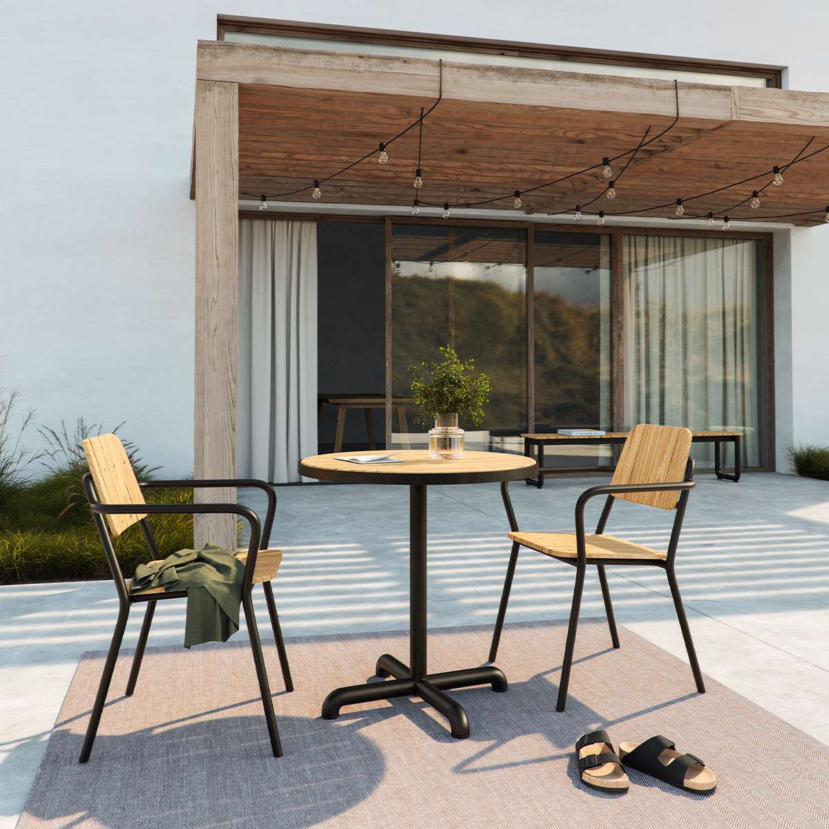 Kirra Café Table rundt utendørsbord med pulverlakkert aluminium og ubehandlet teakplate, taupe eller noir farge.