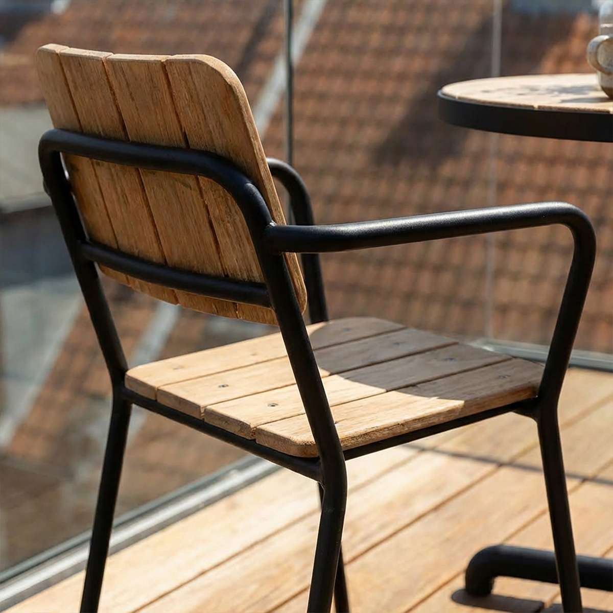 Kirra hagestol fra sackit norway i svart pulverlakkert aluminium med sete og rygg i teak på en solrik terrasse