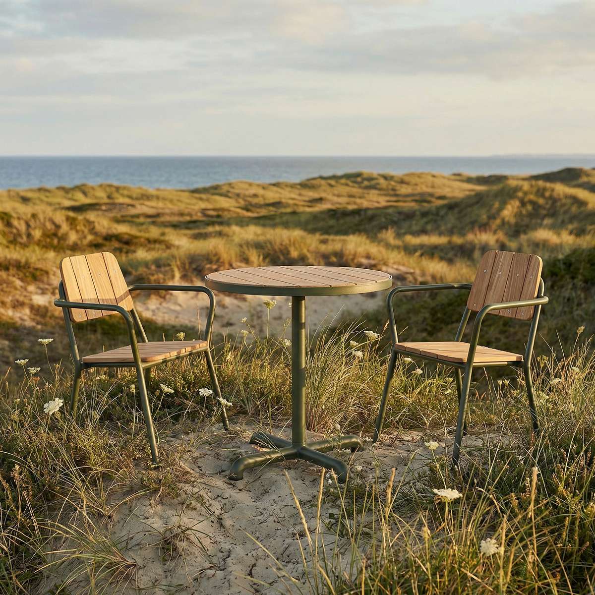 Kirra Café Table utendørs spisebord i pulverlakkert aluminium og ubehandlet teak med rund bordplate.
