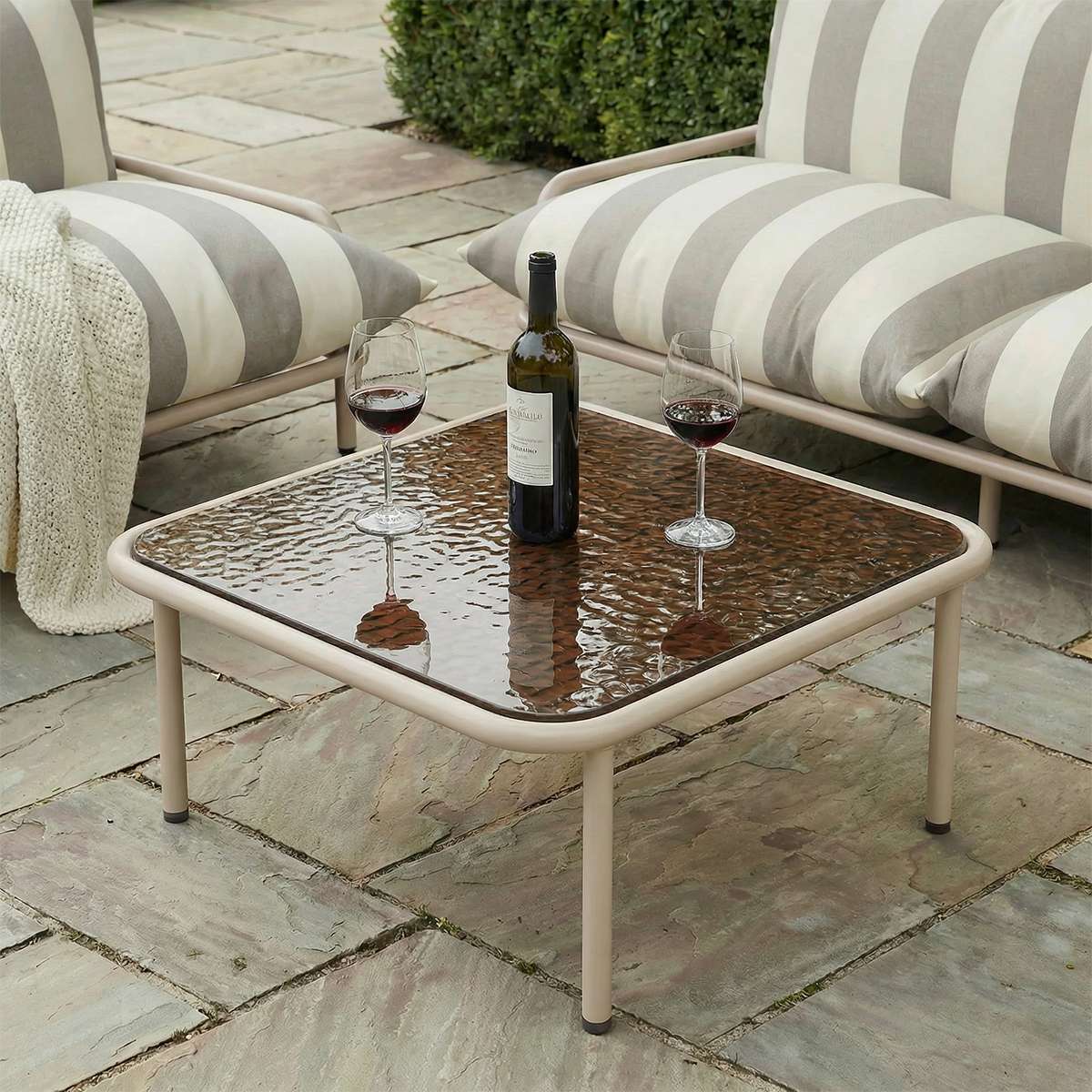 Taupe Mollis Coffee Table med pulverlakkert aluminiumsramme og røykfarget herdet glass, utendørs.