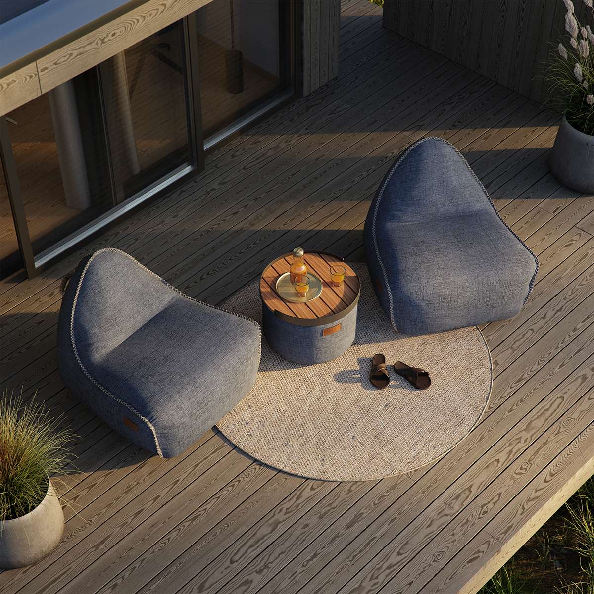 To grå loungestoler fra sackit på en solrik treterrasse med rundt bord og tekstiler i værbestandig design for nordisk utendørsbruk