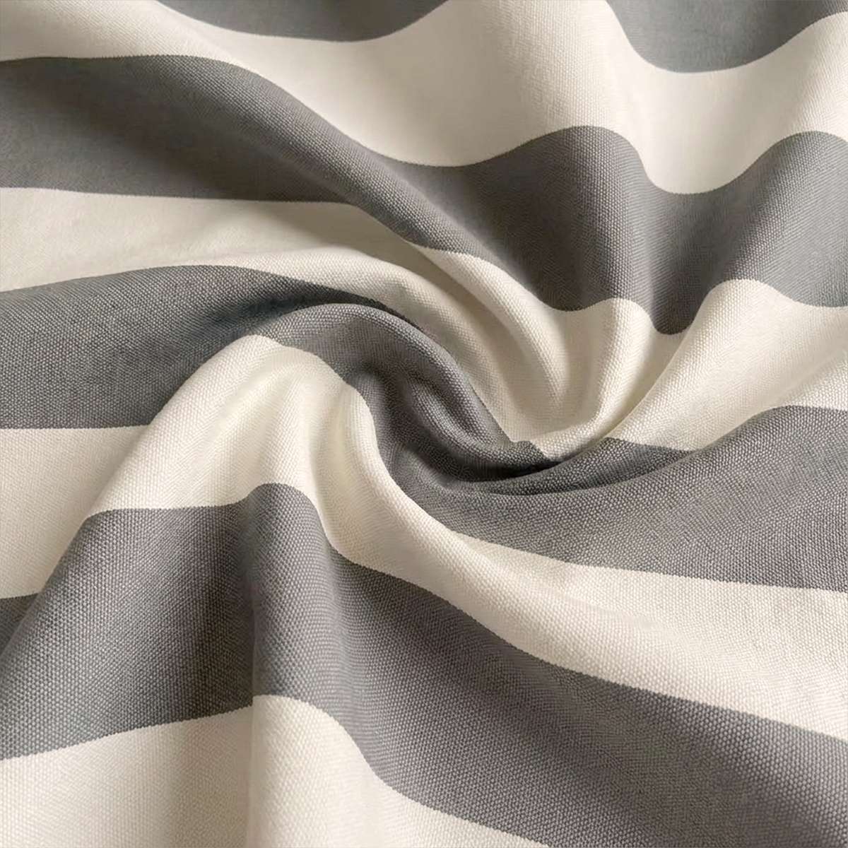 Nærbilde av stripet utendørstekstil i grått og offwhite med vevd struktur og myke folder til sackit loungestol