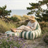 sackit utendørs loungestol med matchende puff i grønne og hvite striper brukt ved kysten omgitt av sanddyner gress og blomster